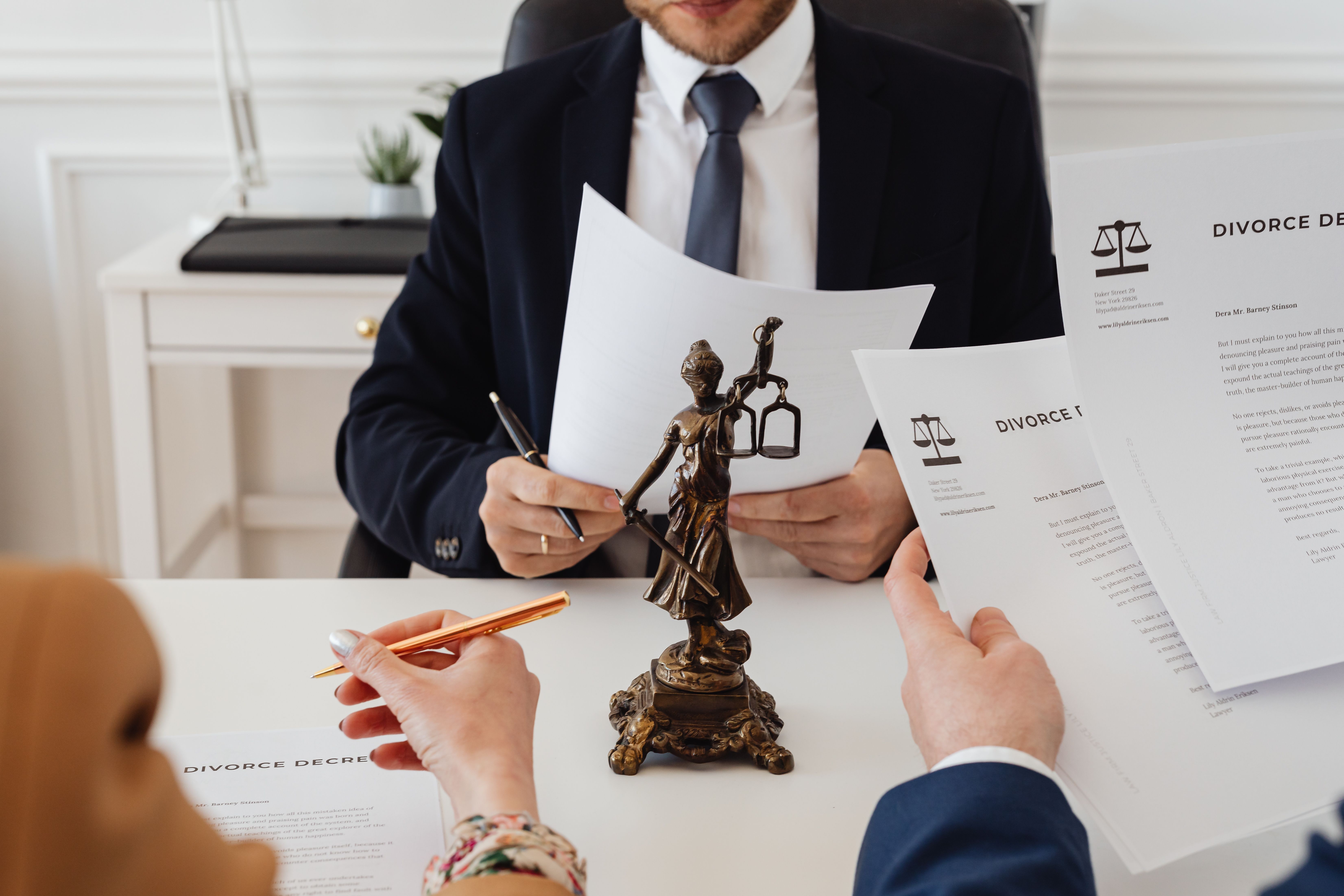 Legal professionals reviewing class action lawsuit documents in a law office beside a Lady Justice statue