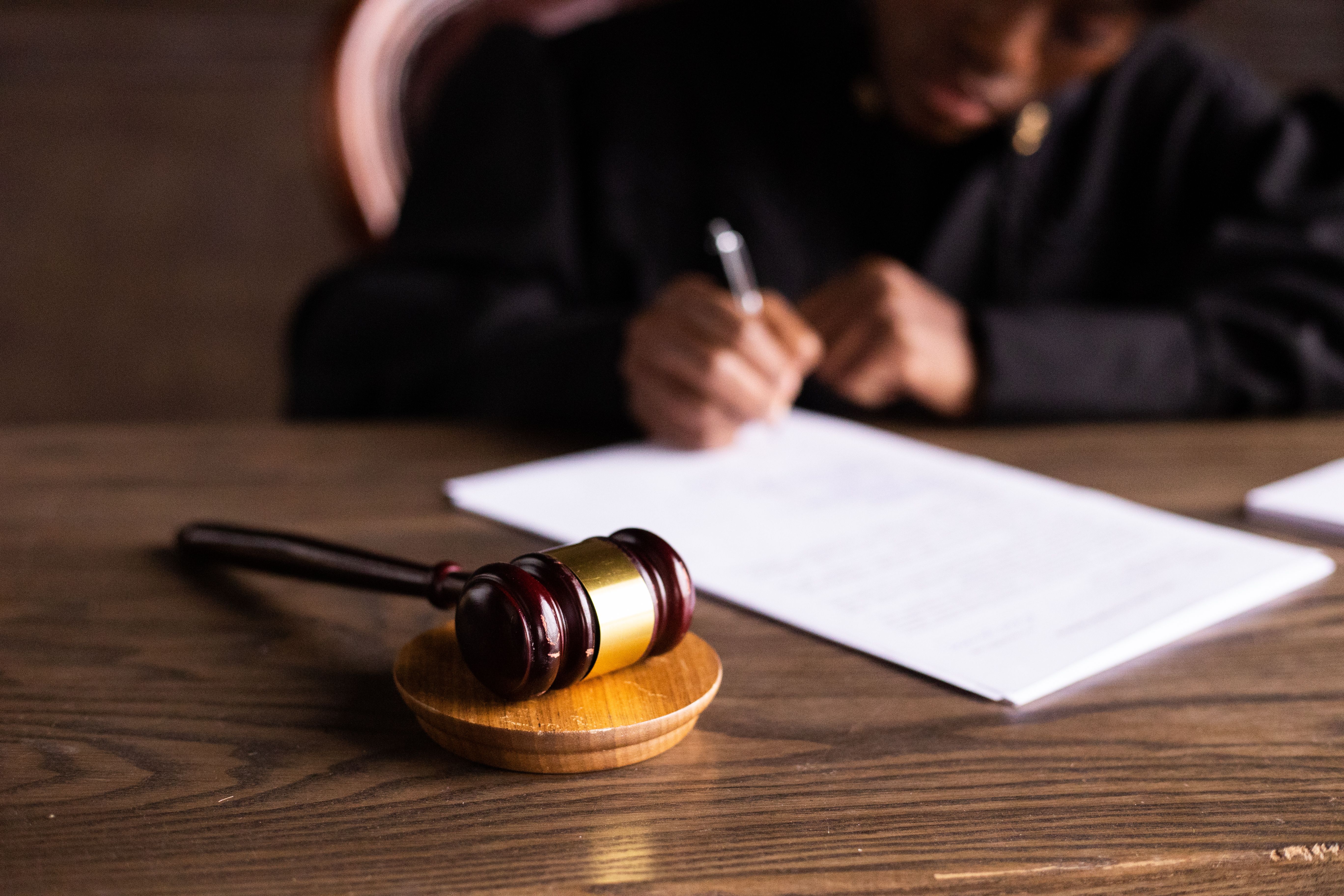 Judge signing legal documents at a desk with a gavel in focus, representing court proceedings in a class action case