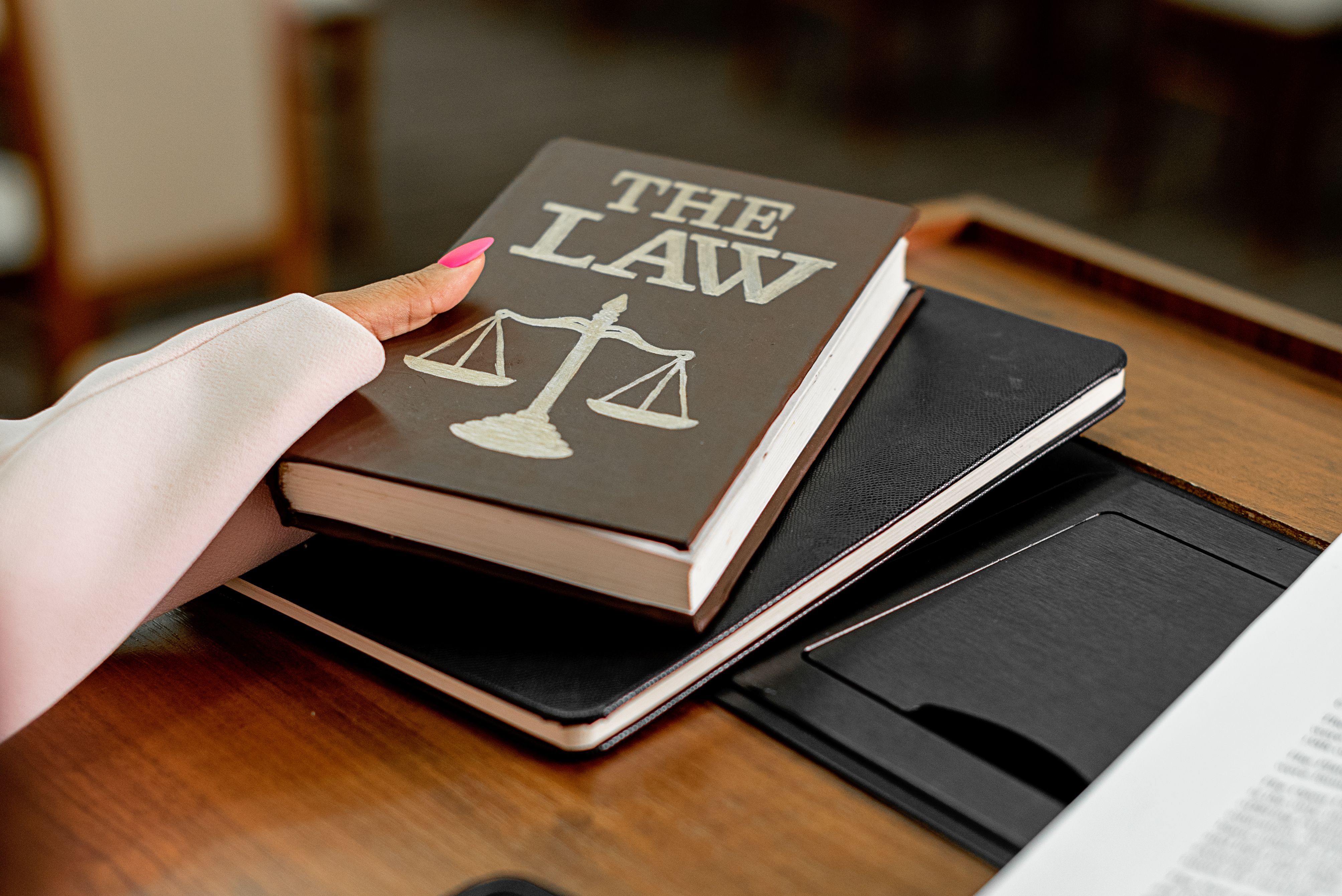 Law book titled The Law on a wooden desk with scales of justice, illustrating legal research for class action lawsuits
