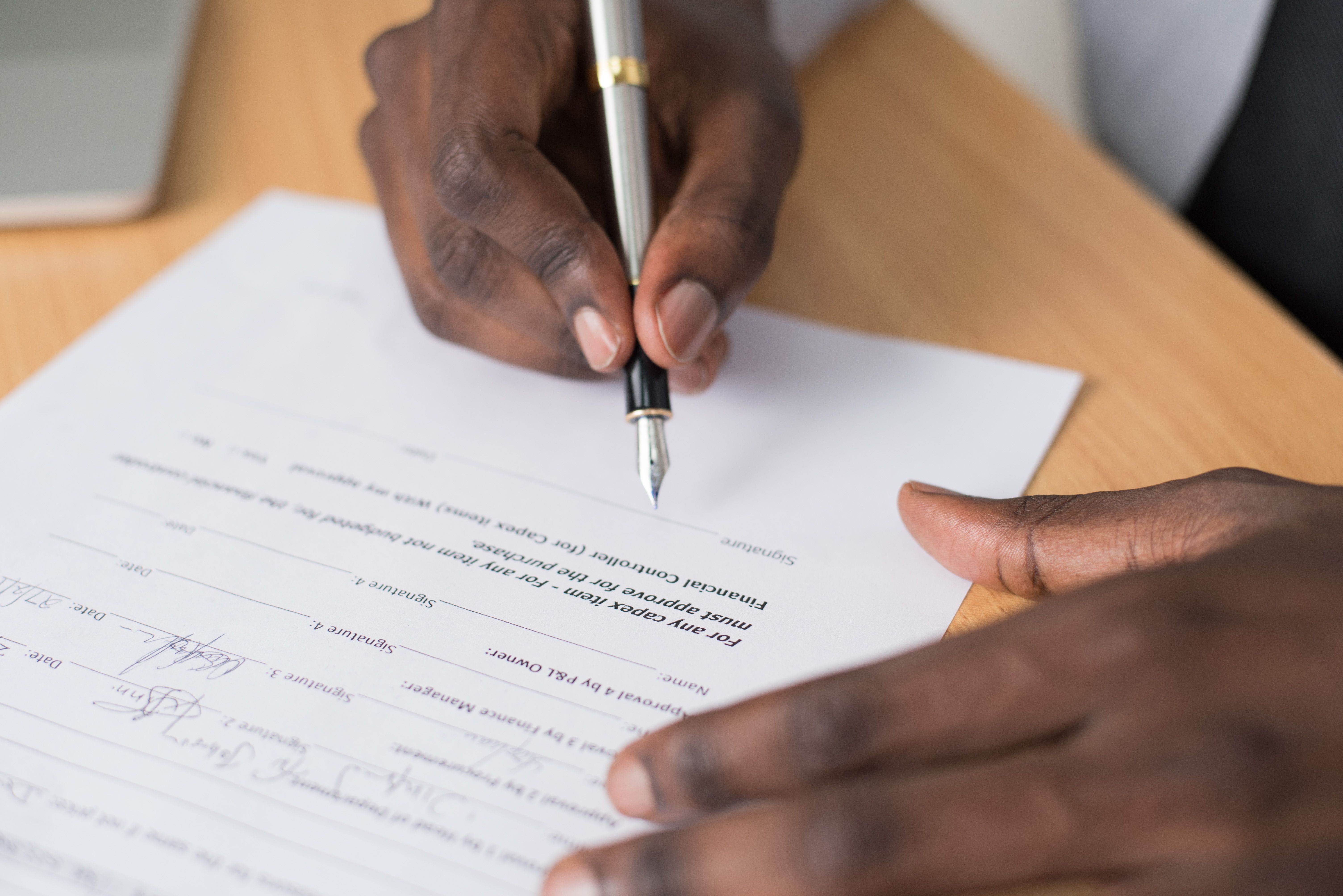 Close-up of a person signing a formal agreement to join a class action lawsuit