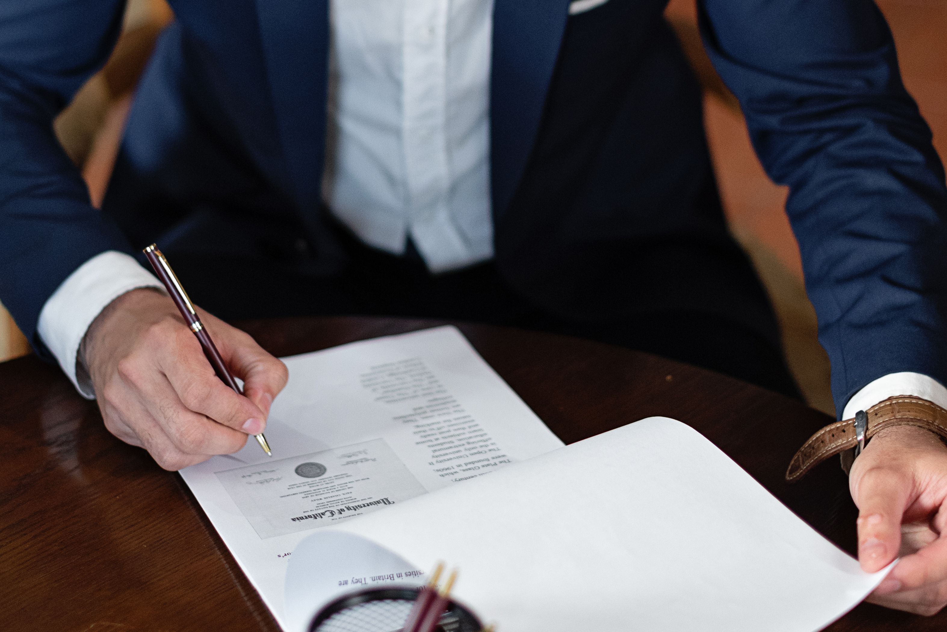 Professional signing legal documents at a desk, depicting the paperwork involved in a cross-border class action